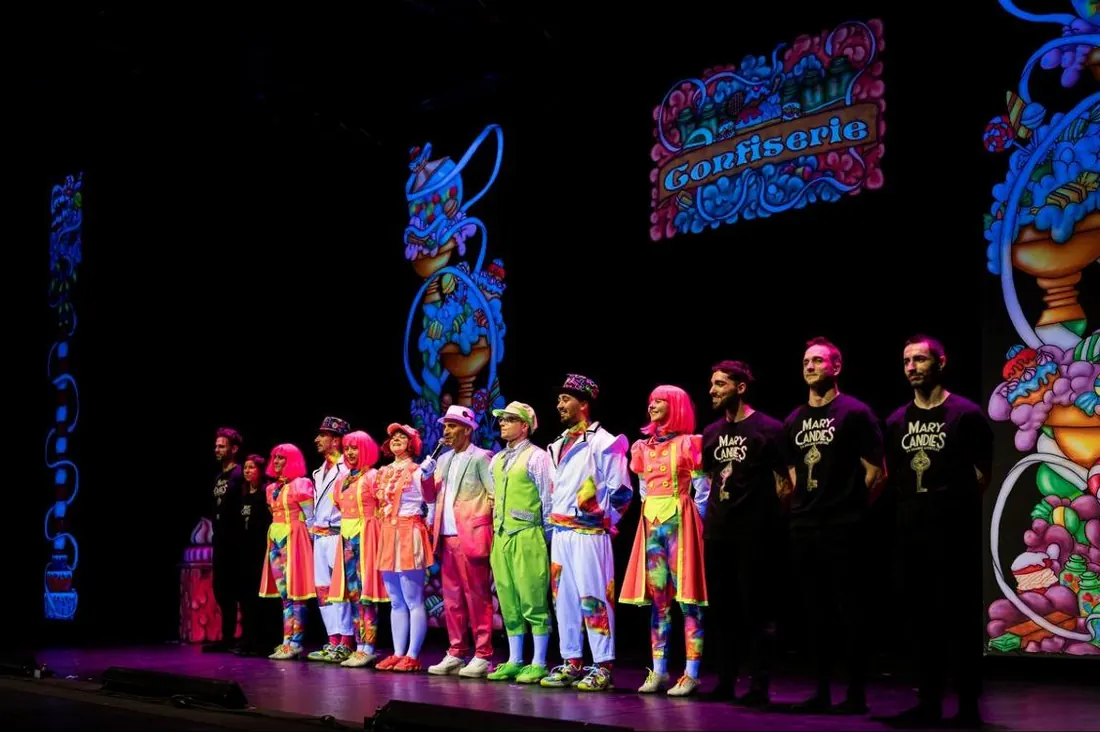 La troupe de Mary Candies sur scène, en costumes colorés, pendant le salut final